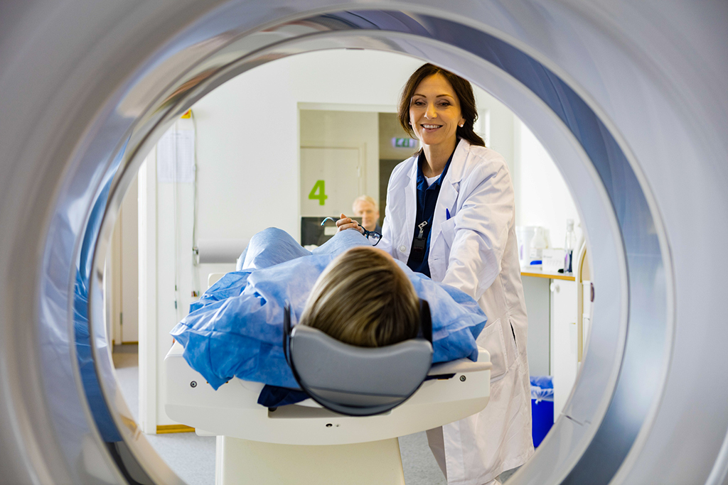 Female Doctor Looking At Patient Undergoing CT Scan