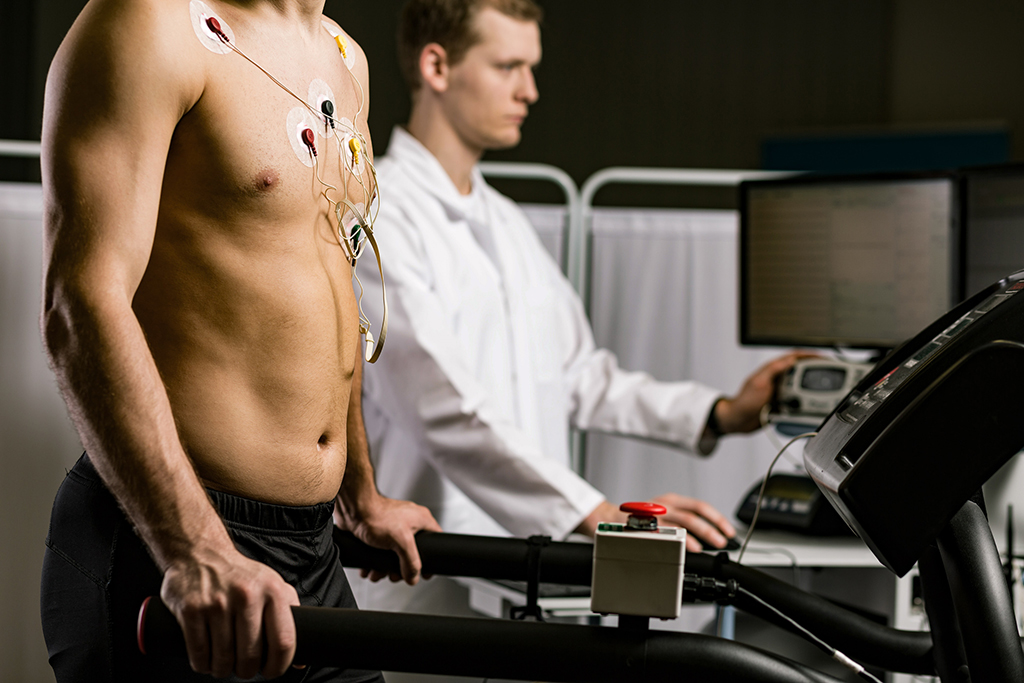 Cropped shot of a shirtless man with electrodes attached to his chest and young doctor in the background